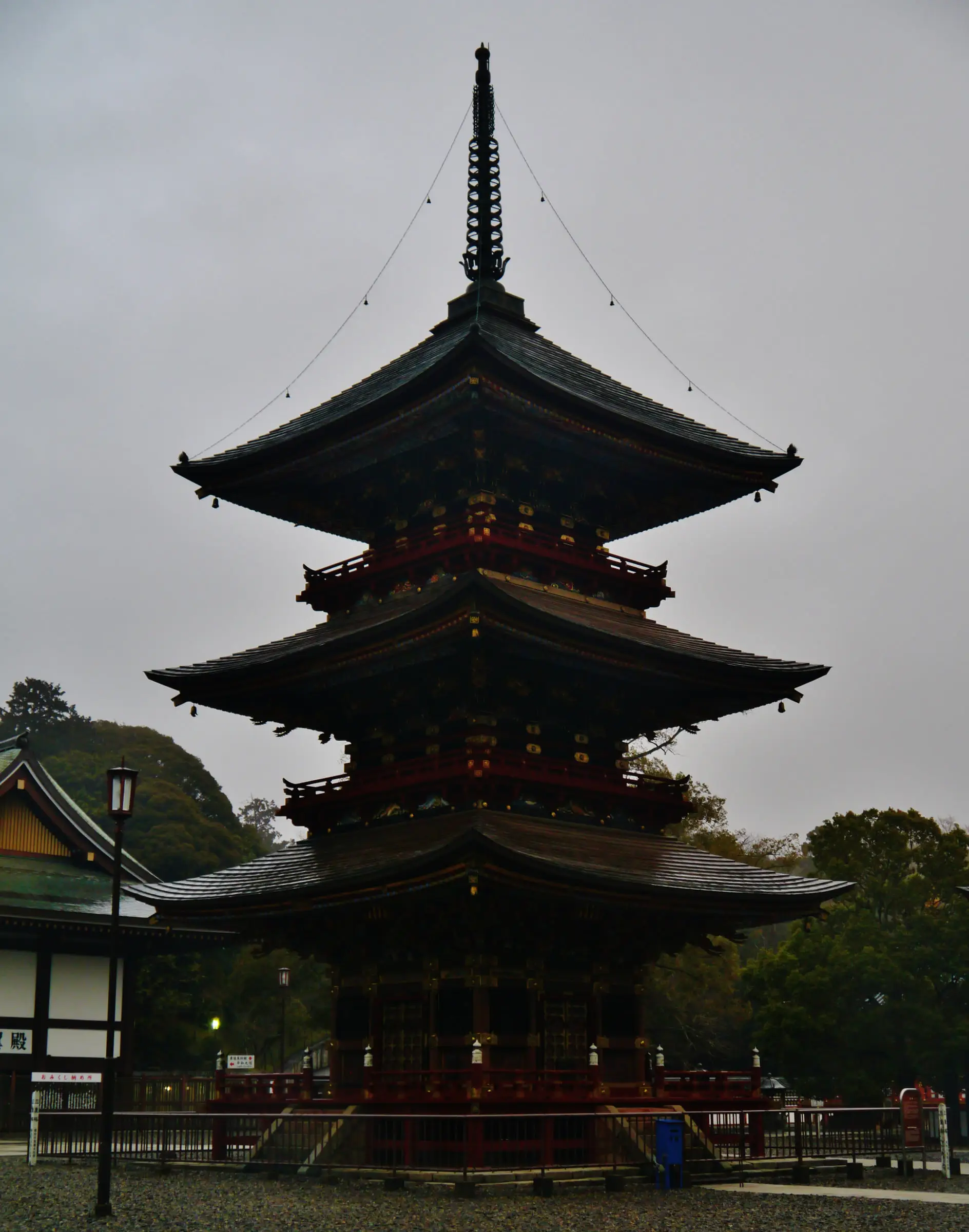曇天の下、木立を背にした三重塔